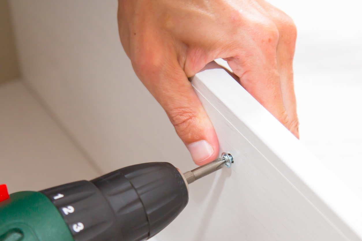 Close Up Of Man Assembling Flat Pack Furniture with a screwdriver