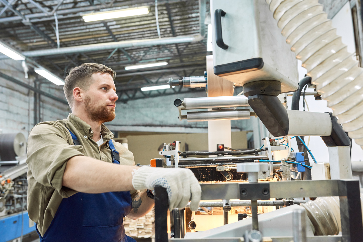 Side view portrait of young factory worker operating machine unit in workshop, copy space